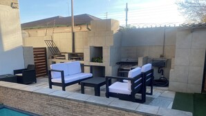 Un área junto a la piscina con sofá, sillas y una mesa.