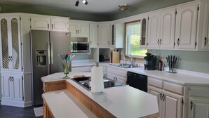 A modern kitchen with white cabinetry, stainless steel appliances, and a central island. - Spacious, pet-friendly home in Hancock Twp. Includes indoor sauna! (Hancock)