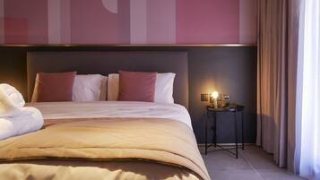 Una habitación de hotel con una cama grande, una mesita de noche con lámpara y una pared decorada con arte abstracto.