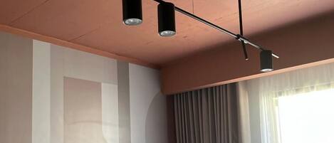 Una habitación de hotel moderna con una cama grande, un cabecero y una lámpara del techo.