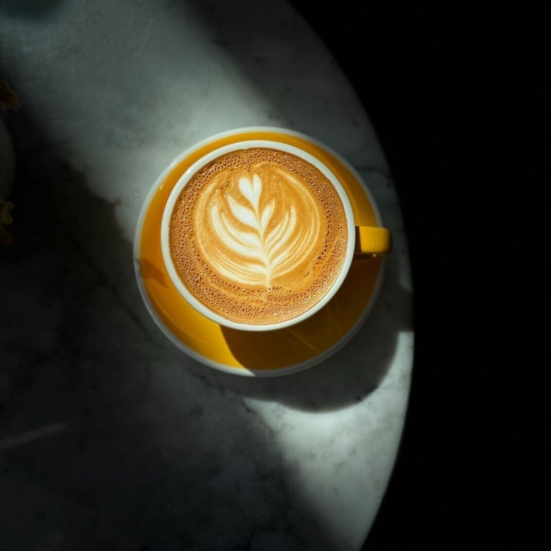 A cup of coffee with latte art on a marble surface.