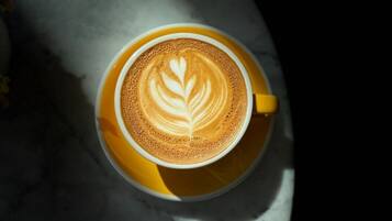 A cup of coffee with latte art on a marble surface.