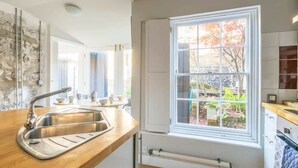 Una cocina con encimera de madera, pileta de acero inoxidable y ventana con vista a follaje.