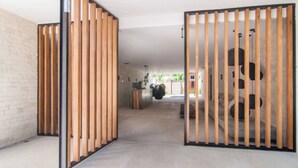 A modern interior with a concrete floor, a brick wall, and a wooden partition with vertical slats. - Increíble Departamento con Piscina y Gym (Tulum)