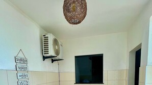 Un petit coin repas avec une table et des chaises, un luminaire suspendu et un climatiseur fixé au mur.