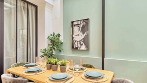 A dining area with a wooden table set for four, surrounded by cushioned chairs. There are potted plants and a framed artwork on the wall. - Sublime AC Apartment 3 bedrooms Saint Germain (Paris)