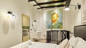 A modern hotel room with a bed, a bathroom, and a colorful mosaic wall. - Sublime AC Apartment 3 bedrooms Saint Germain (Paris)