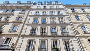 A multi-story building with balconies, large windows, and a sign indicating a restaurant. - Sublime AC Apartment 3 bedrooms Saint Germain (Paris)