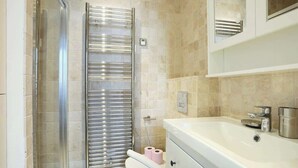 A modern bathroom with a glass shower enclosure, a white sink with a chrome faucet, and a toilet with a towel rack.