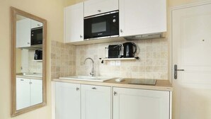 A kitchen with white cabinets, a Bosch microwave, a coffee maker, and a sink.