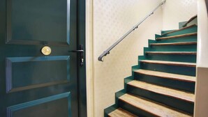 A staircase with wooden steps and a metal handrail, leading to a door with a brass doorknob. - Sublime and new Studio Le Marais / Beaubourg (Paris)