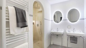 Ein modernes Badezimmer mit bodenebenen Dusche, zwei Waschbecken und einem großen Spiegel.