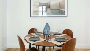A dining area with a round table set for four, a blue vase centerpiece, and a framed picture above the table. - Elegant Apartment at the Palais Royal Opera (Paris)