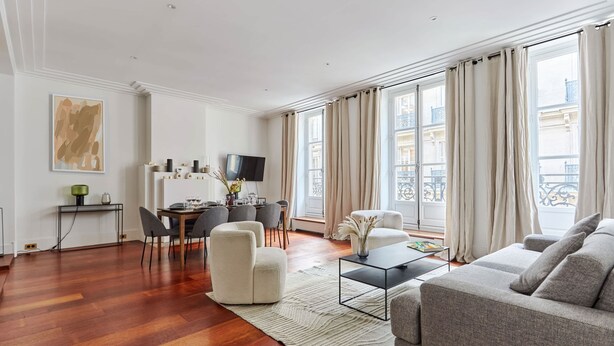 Una sala de estar moderna con sofá, sillones, una mesa de comedor y televisión.