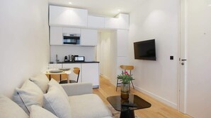 Una sala de estar moderna con un sofá, una mesa de centro y un televisor montado en la pared.