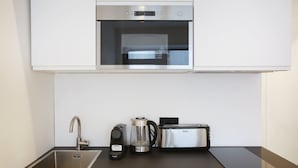 Una cocina moderna con un horno de acero inoxidable, una cafetera, un hervidor y un tostador sobre la encimera.
