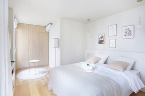 Quarto moderno com uma cama grande, uma mesinha redonda e um guarda-roupa de madeira.