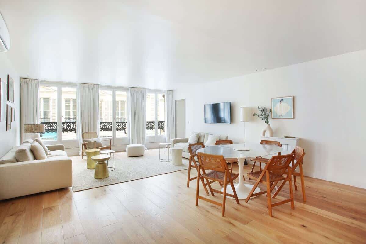 Un salon spacieux avec une grande table à manger, des sièges confortables et une vue sur un balcon.
