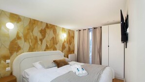 A hotel room with a bed, a TV mounted on the wall, and a window with curtains.