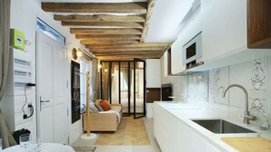 Una cocina moderna con una isla grande, muebles blancos y techo de madera.