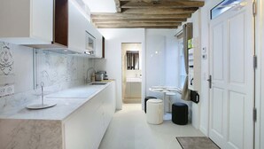 Una cocina moderna con encimeras de mármol, vigas de madera y vista al baño contiguo.