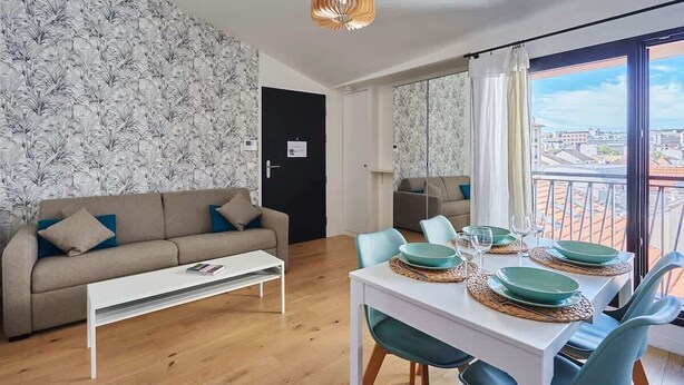 A modern living room with a sofa, coffee table, dining table set with plates and glasses, and a balcony with a view. - Apartment Boulogne facing the "Passage" (Boulogne-Billancourt)