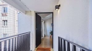 Ein schmaler Korridor mit schwarzem Geländer an einer Seite und weißer Wand an der anderen.