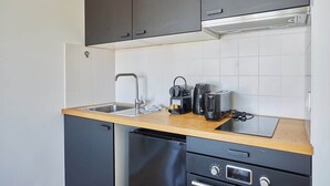 Eine kompakte Küche mit Spüle, Toaster, Wasserkocher und Geschirrspüler.