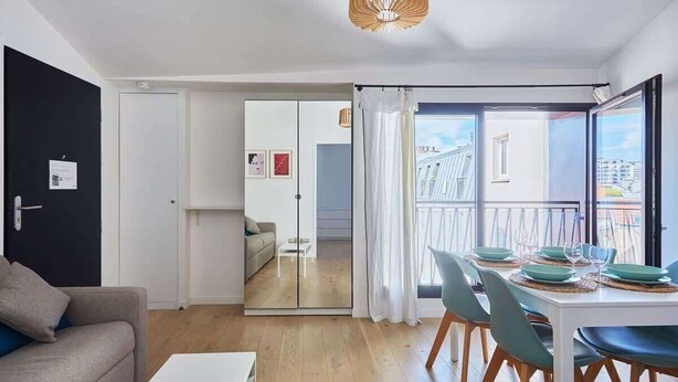 Eine moderne Wohnung mit Essbereich, Wohnzimmer und einem Balkon mit Blick auf die Stadt.