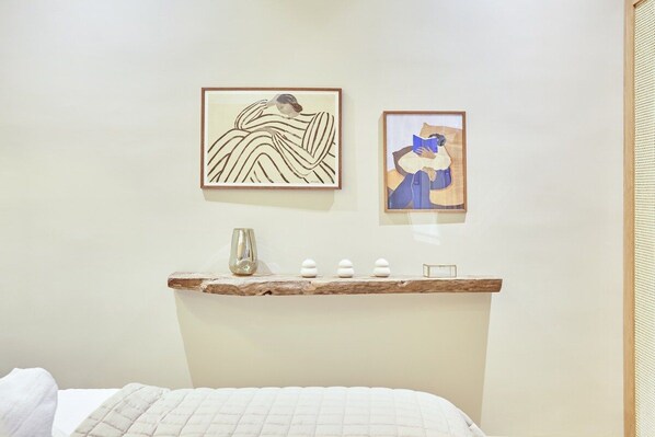A bedroom with a bed, a shelf with decorative items, and two framed artworks on the wall. - Sublim et new apartment Place des Vosges (Paris)