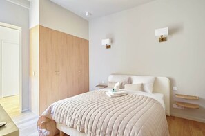 A modern bedroom with a large bed, wooden wardrobe, and two wall-mounted lights. - Sublim et new apartment Place des Vosges (Paris)