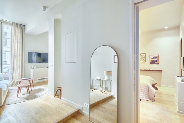 Una sala de estar moderna con un sofá, un televisor, una mesa de centro y un espejo.