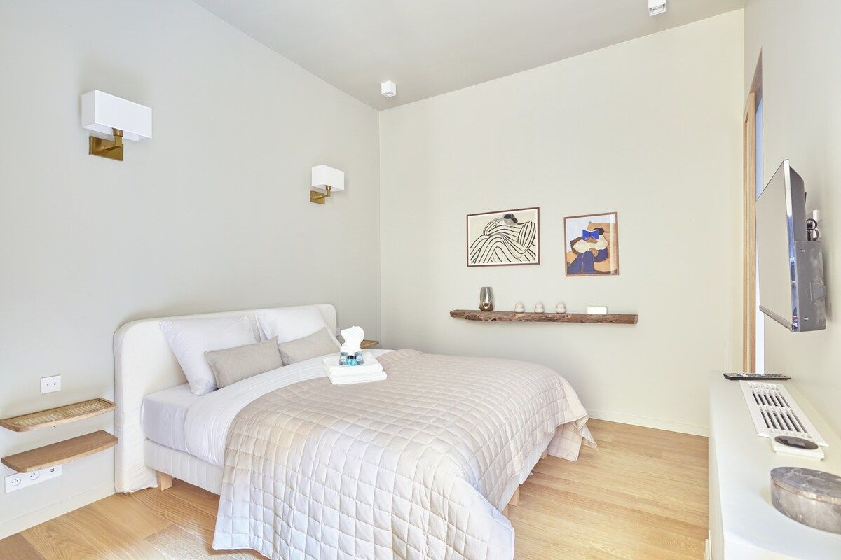 Ein Schlafzimmer mit Bett, Nachttischen, einem Fernseher und Bildern an der Wand.