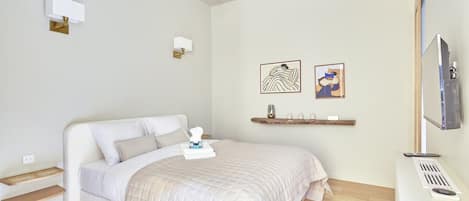 Un dormitorio con cama, mesitas de noche, televisión y obras de arte en la pared.