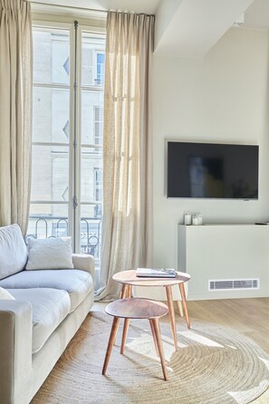 Ein modernes Wohnzimmer mit einer Couch, einem Couchtisch und einem an der Wand montierten Fernseher.