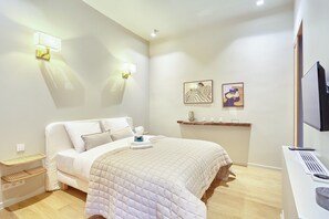 A hotel room with a bed, bedside tables, a desk with a computer, and wall-mounted artwork. - Sublim et new apartment Place des Vosges (Paris)