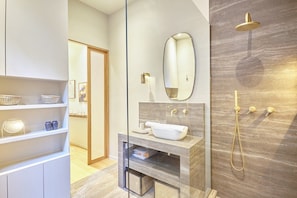 A modern bathroom with a freestanding bathtub, a large mirror, and a shower with a gold showerhead.