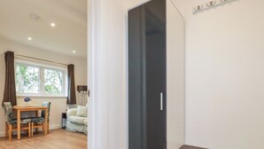 Une pièce avec un plancher en bois, une table à manger avec des chaises, un canapé et un meuble noir.