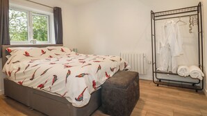 Une chambre à coucher avec un lit, une fenêtre, un radiateur et un portant à vêtements.