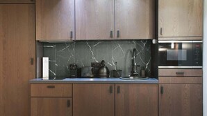 A modern kitchen with wooden cabinets, a marble backsplash, and a built-in microwave. - Modern Suite  Center of Paris Montmartre (Paris)