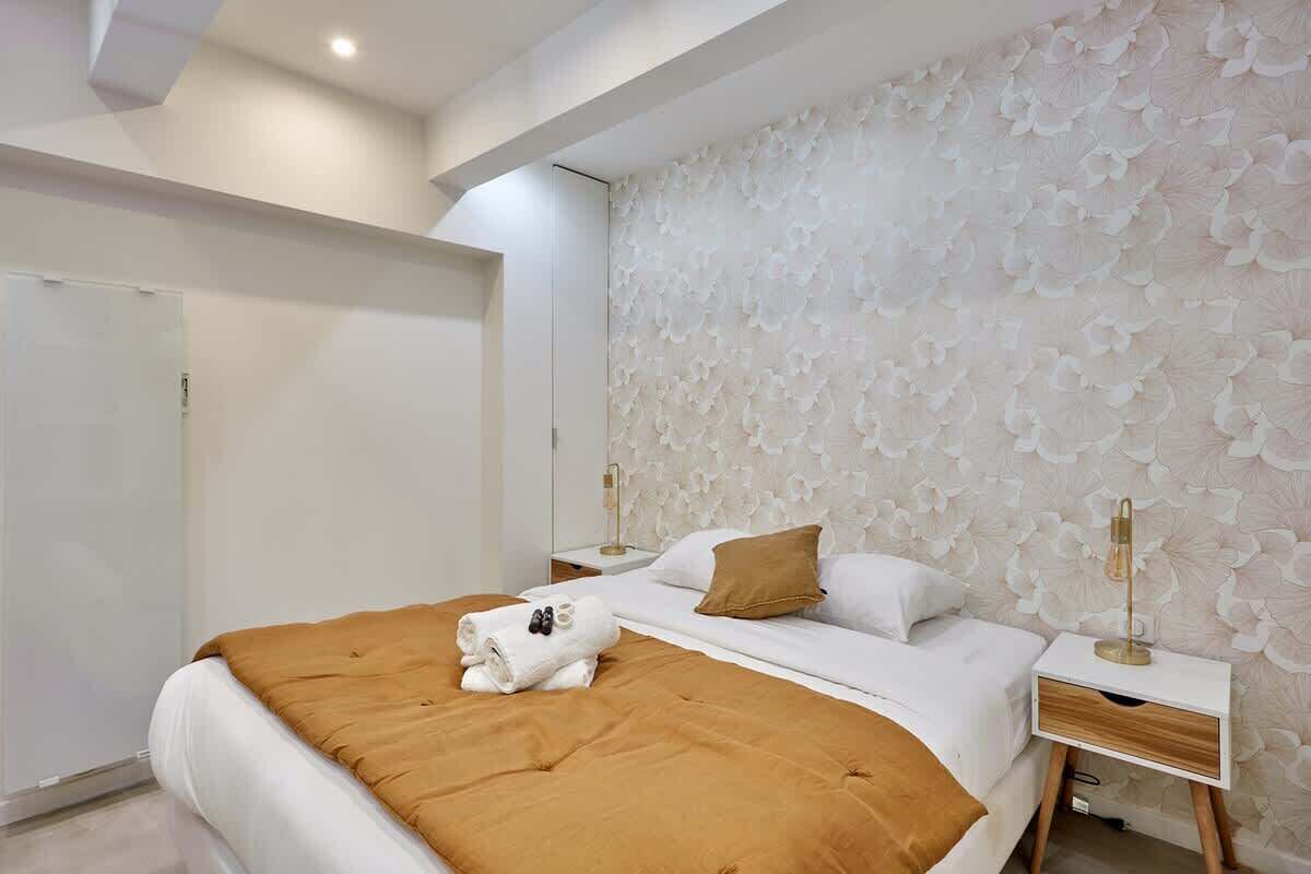 A modern bedroom with a large bed, a nightstand, a wardrobe, and a decorative wall.