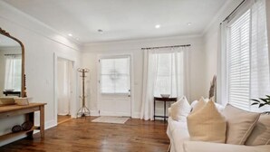 Un salon spacieux doté d’un parquet, d’un canapé beige et d’un grand miroir.