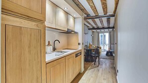 A modern kitchen with wooden cabinets, a white countertop, and a built-in dishwasher. - Charming apartment Center of Paris/Montorgueil (Paris)