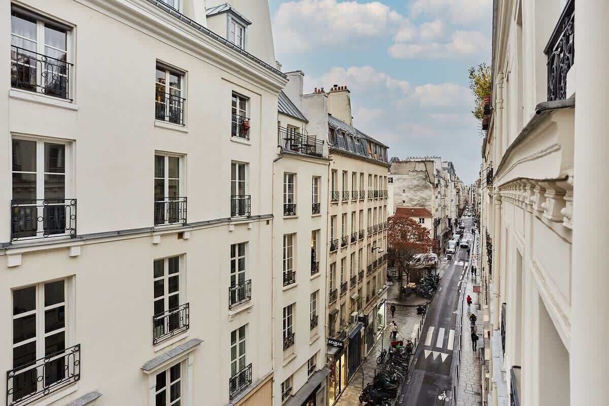 A narrow street flanked by multi-story buildings with balconies and windows.