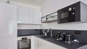 A modern kitchen with white cabinets, a built-in oven, a microwave, and a coffee maker. - Charming Apartment Center of Paris-Montorgueil (Paris)