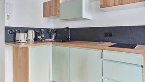 Una cocina moderna con encimera de madera, salpicadero negro y armarios de colores claros.