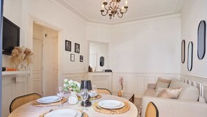 A dining room with a round table set for four, surrounded by wicker chairs. - Eiffel Tower Terrace Apartment (Paris)
