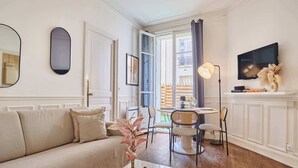 A living room with a sofa, coffee table, and a dining area with chairs and a table. - Eiffel Tower Terrace Apartment (Paris)