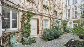 A narrow cobblestone pathway leading to a building with a white door and windows. - Amazing apartment in the Center of Paris ( Marais) (Paris)