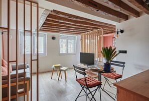 Relax in this spacious living area with a sofa, chairs, and a TV, surrounded by natural light and a potted plant.